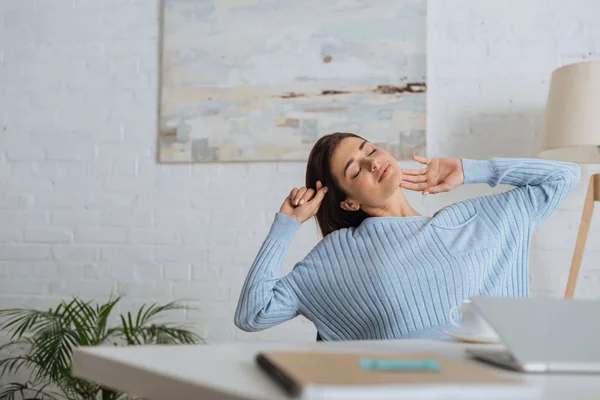 Selektiver Fokus einer verträumten Frau, die sich am heimischen Tisch dehnt — Stockfoto