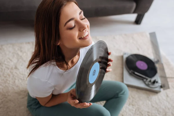 Selective focus of cheerful girl holding retro vinyl record at home — Stock Photo