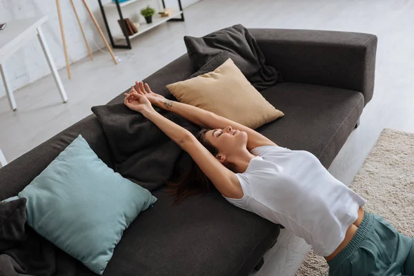 Мечтательная молодая женщина с закрытыми глазами отдыхает на диване — стоковое фото