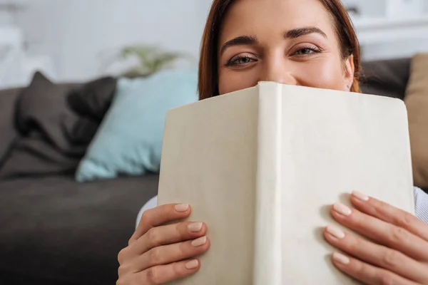 Selective focus of young woman covering face with book — Stock Photo