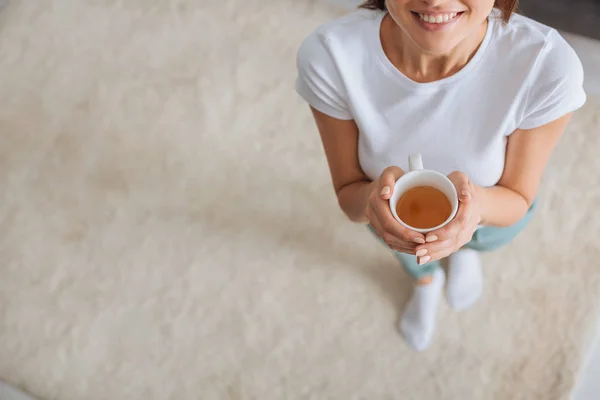 Cropped view of happy girl holding cup with tea — Stock Photo