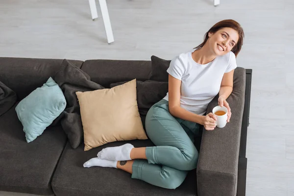 Overhead view of dreamy girl chilling of sofa with cup of tea — Stock Photo