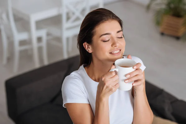 Mulher feliz sonhando e cheirando xícara de chá — Fotografia de Stock