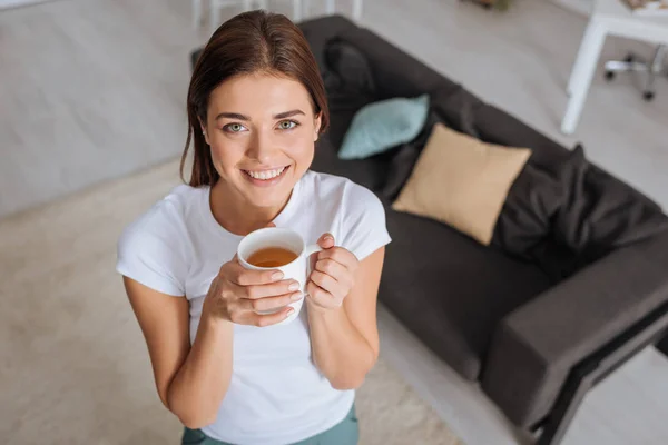 Overhead view of attractive woman smiling while holding cup of tea — Stock Photo