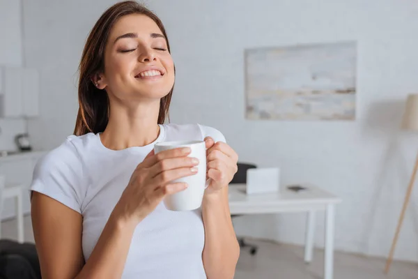 Cheerful woman dreaming while holding cup of tea — Stock Photo