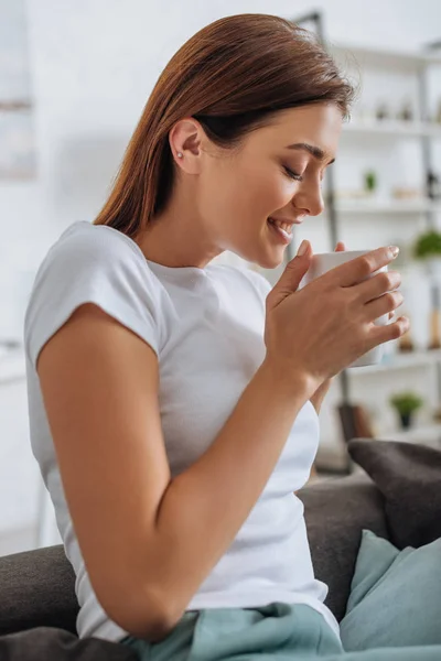 Young attractive woman with closed eyes holding cup with tea — Stock Photo