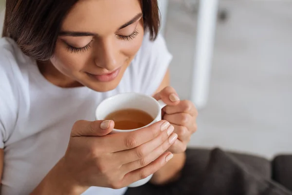 Vista aérea de mujer joven con los ojos cerrados sosteniendo taza con té - foto de stock