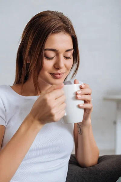 Jeune femme aux yeux fermés tenant une tasse de thé — Photo de stock