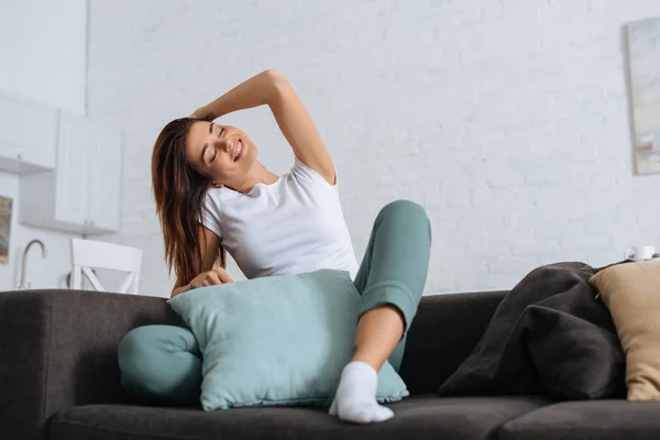 Мечтательная девушка с закрытыми глазами расслабляется на диване с подушками — стоковое фото