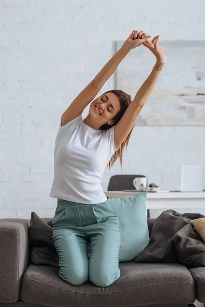 Smiling woman stretching while chilling on sofa in living room — Stock Photo