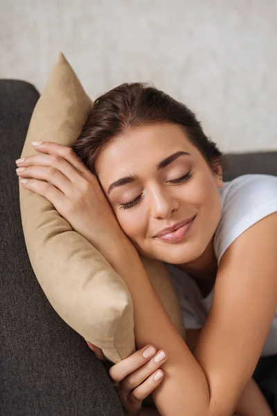 Mujer sonriente con los ojos cerrados escalofriante mientras está acostado en la almohada - foto de stock