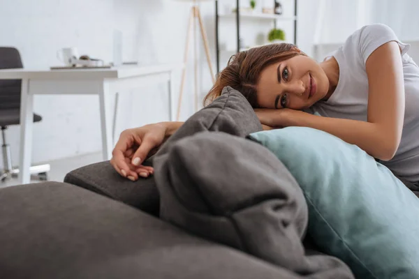 Enfoque selectivo de la hermosa mujer joven relajándose en el sofá en casa - foto de stock