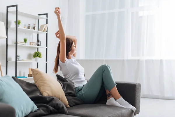 Selective focus of young dreamy woman with outstretched hand relaxing in living room — Stock Photo