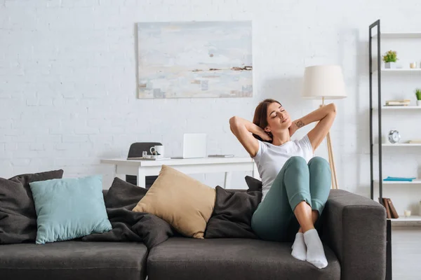 Feliz joven sentada en el sofá en la sala de estar — Stock Photo