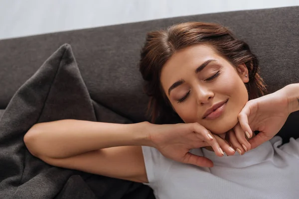 Vue de dessus de la belle femme rêvant tout en se reposant sur le canapé dans le salon — Photo de stock