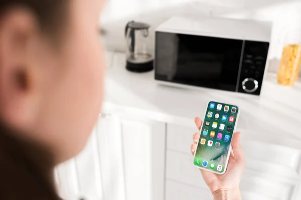 KYIV, UCRANIA - 9 de octubre de 2019: vista recortada de una mujer sosteniendo un teléfono inteligente con interfaz de Apple - foto de stock