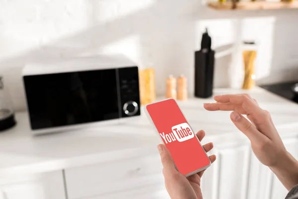 KYIV, UCRANIA - 9 de octubre de 2019: vista recortada de la mujer sosteniendo el teléfono inteligente con la aplicación de youtube - foto de stock