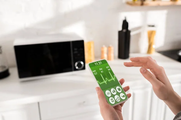 Cropped view of woman holding smartphone with health app — Stock Photo