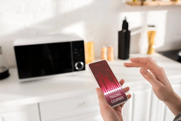 Cropped view of woman holding smartphone with trading courses app — Stock Photo