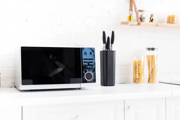 Microwave, pasta and knives on surface in kitchen — Stock Photo