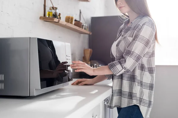 Cropped view of woman in shirt using microwave in kitchen — Stock Photo