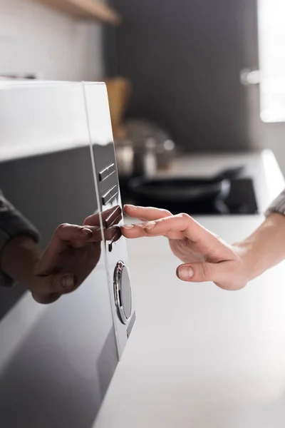 Cropped view of woman using microwave in kitchen — Stock Photo