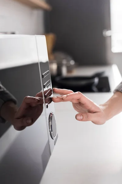 Vista recortada de la mujer usando microondas en la cocina - foto de stock