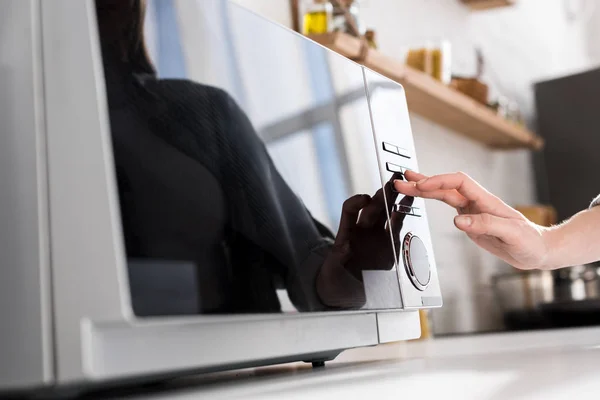 Cropped view of woman using microwave in kitchen — Stock Photo