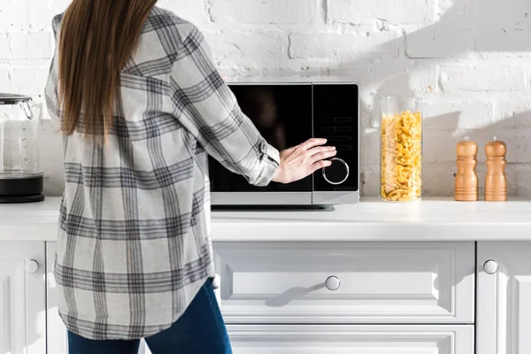 Vista cortada da mulher na camisa usando microondas na cozinha — Fotografia de Stock