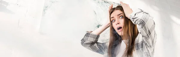 Plano panorámico de mujer impactada y atractiva mirando hacia otro lado y tocando la cabeza - foto de stock