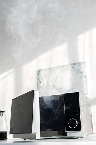 Broken and steamy microwave on table in kitchen — Stock Photo