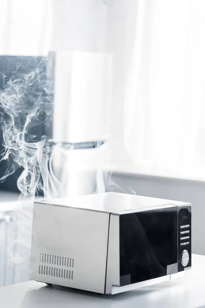 Kaputte und dampfende Mikrowelle auf dem Tisch in der Küche — Stockfoto
