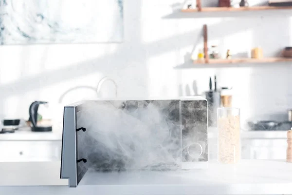 Broken and steamy microwave on table in kitchen — Stock Photo