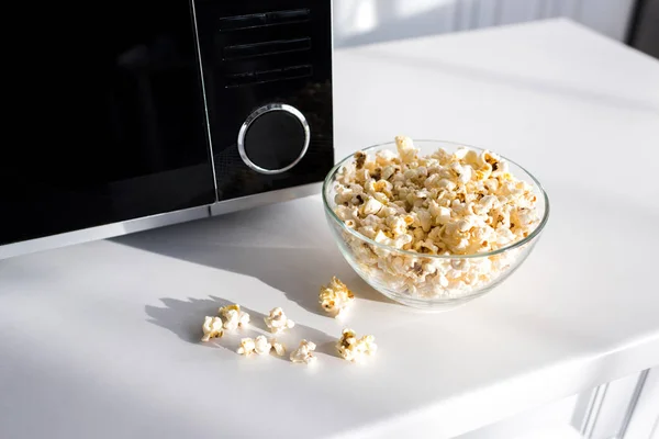 Popcorn in bowl near microwave on table in kitchen — Stock Photo