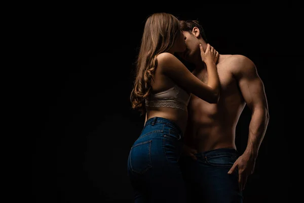 Sexy joven pareja besos aislado en negro - foto de stock