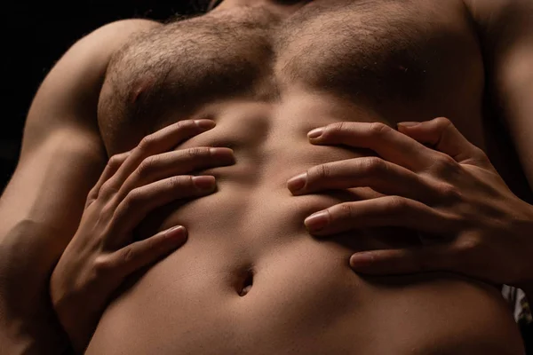 Abgeschnittene Ansicht von Frau umarmt sexy jungen Mann mit muskulösem Oberkörper isoliert auf schwarz — Stockfoto