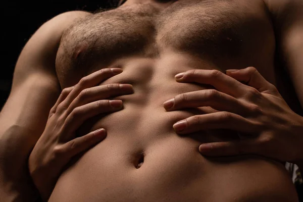 Vista ritagliata di donna che abbraccia sexy giovane uomo con busto muscolare isolato su nero — Foto stock