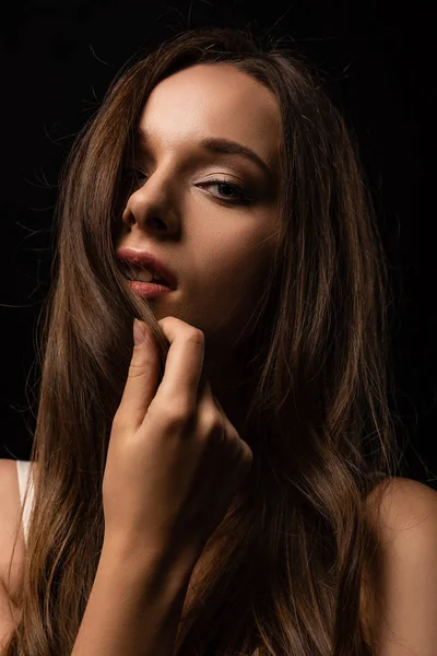 Sexy young girl touching hair isolated on black — Stock Photo