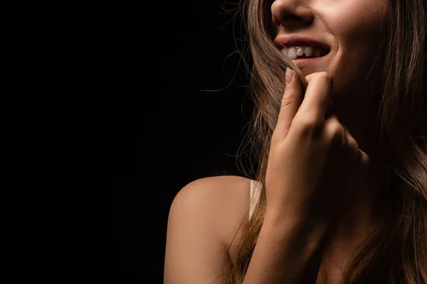 Vista ritagliata di sorridere sexy ragazza toccando i capelli isolati su nero — Foto stock