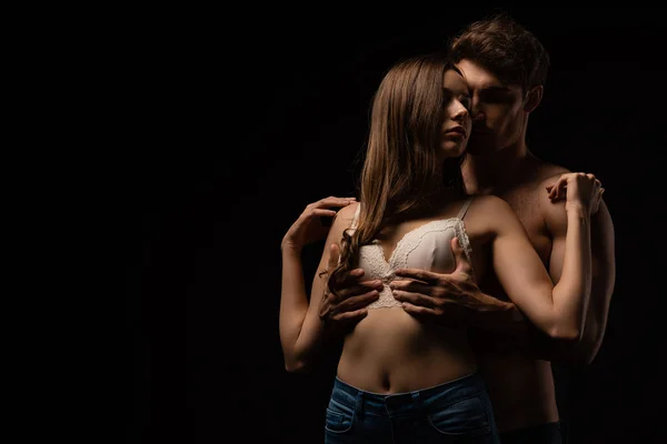 Passionate young man touching breast of girlfriend isolated on black — Stock Photo