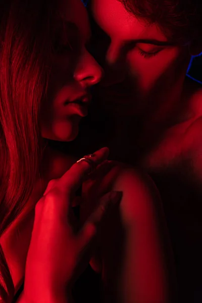 Undressed sexy young couple kissing and hugging in red light — Stock Photo