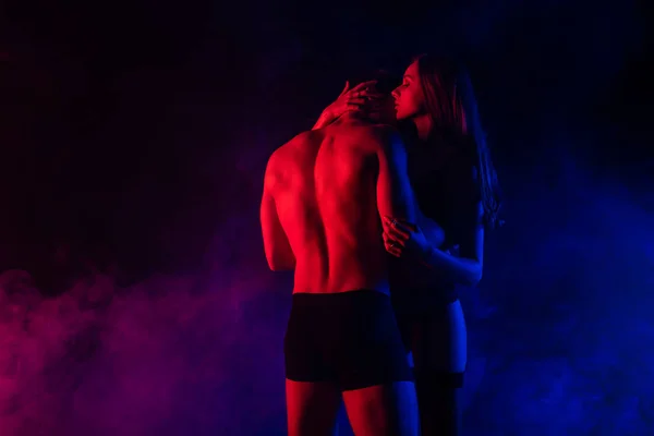 Passionate undressed sexy young woman kissing boyfriend in red light — Stock Photo