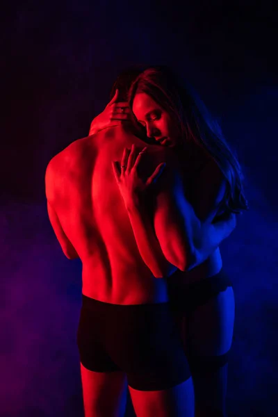 Passionate undressed sexy young couple hugging in red light — Stock Photo