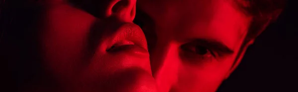 Крупный план страстной молодой пары, целующейся на красном свете, панорамный снимок — стоковое фото