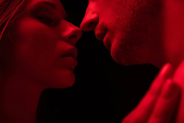 Пристрасна сексуальна молода пара цілується в червоному світлі ізольовано на чорному — стокове фото