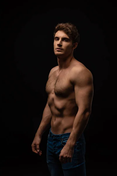 Sexy man in jeans with bare muscular torso isolated on black — Stock Photo