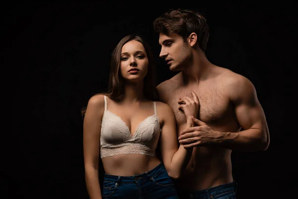 Passionate undressed sexy young couple in jeans isolated on black — Stock Photo