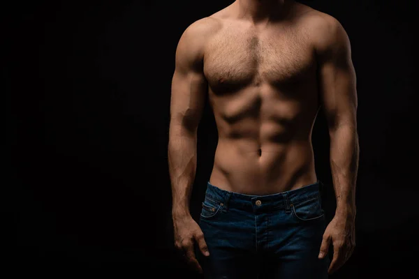 Cropped view of sexy man in jeans with bare muscular torso isolated on black — Stock Photo
