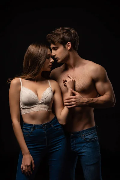 Passionate undressed sexy young couple in jeans isolated on black — Stock Photo