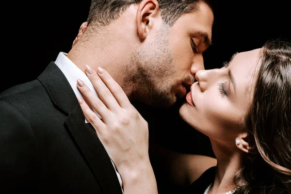 Hombre besándose con hermosa mujer aislado en negro - foto de stock
